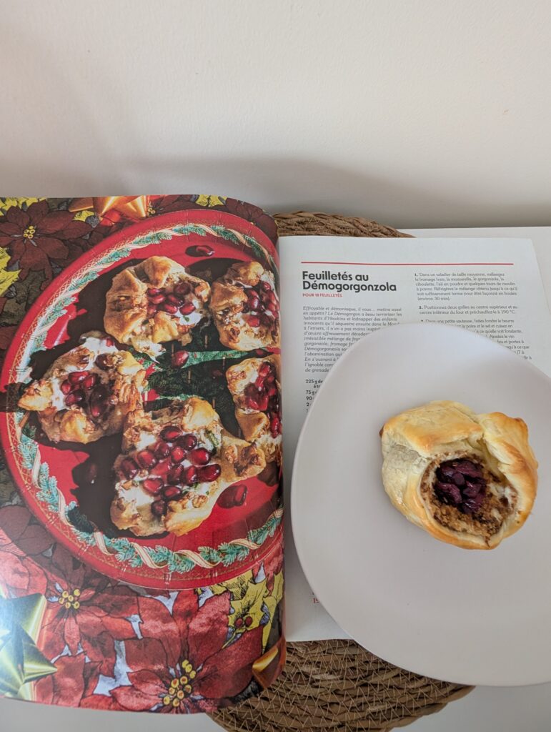 Feuilleté au Démogorgonzola présenté sur une assiette blanche, à côté d'un magazine ouvert, dans un cadre convivial et chaleureux.