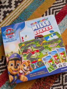 Jeu de société Mon Premier Mille Bornes pour enfants, avec personnages Paw Patrol, sur tapis coloré.