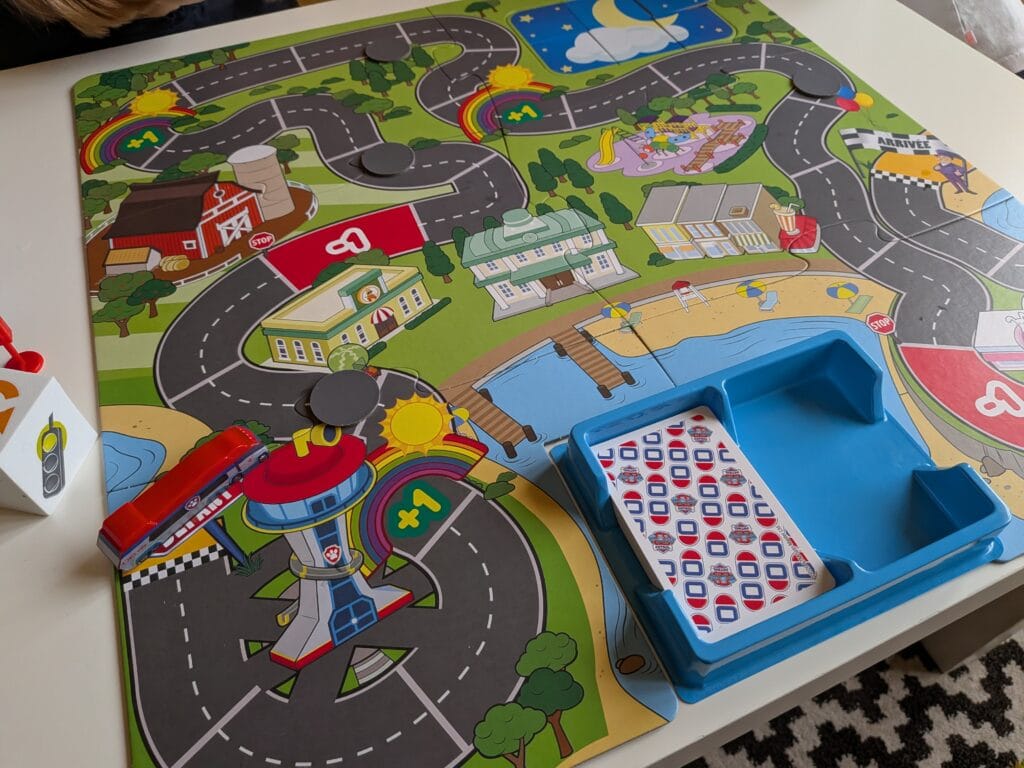 Plateau de jeu coloré avec routes, bâtiments et accessoires pour enfants, idéal pour jouer en famille ou entre amis.
