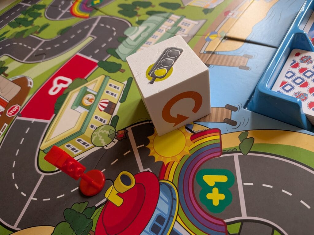 Jeu de société coloré avec des pièces, un dé et un plateau de jeu illustré pour enfants.
