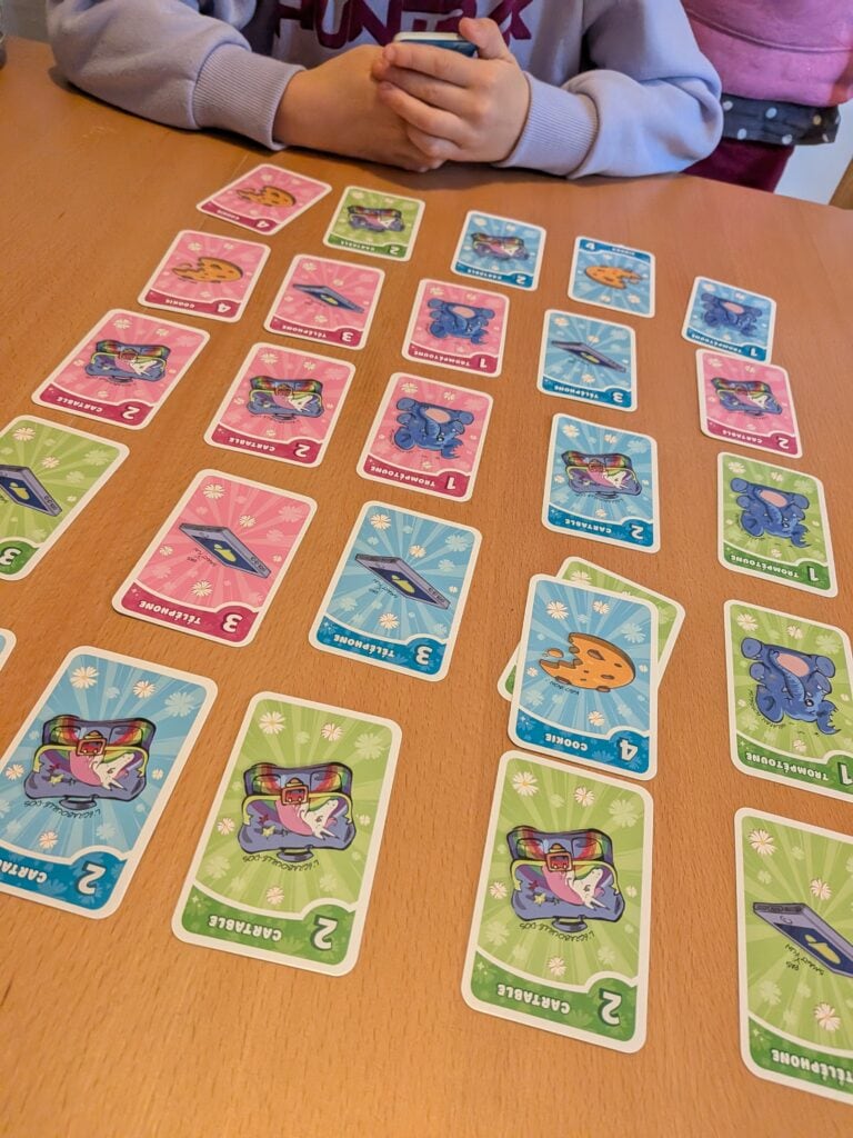 Jeunes enfants jouant à un jeu de cartes coloré avec des illustrations de créatures fantastiques.