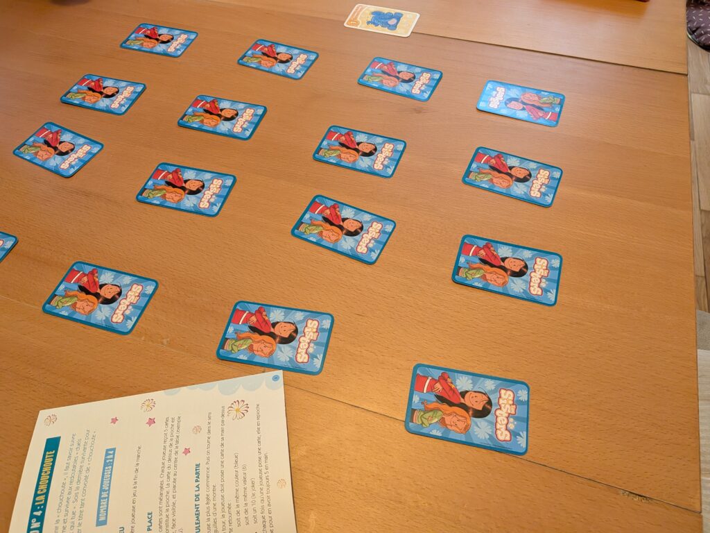 Cartes du jeu Les Sisters avec Marine et Wendy, étalées sur une table en bois.