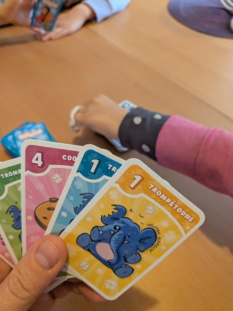 Groupe d'enfants jouant à un jeu de cartes coloré lors d'une réunion familiale.