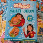 Jeu de société Les Sisters Multi-Jeux avec illustrations de Marine et Wendy, proposant 4 jeux en 1 pour s'amuser en famille.